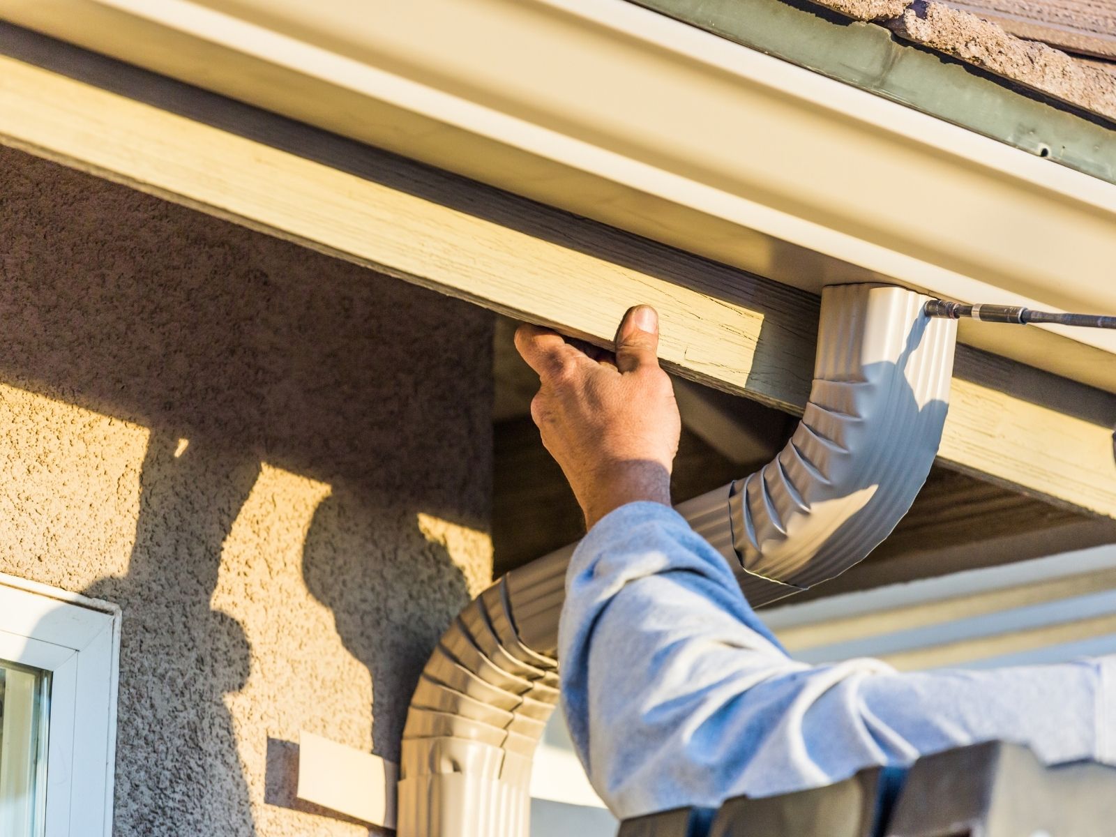 Pointing out faulty gutter connection under shingle roof – expert gutter inspection and repairs.