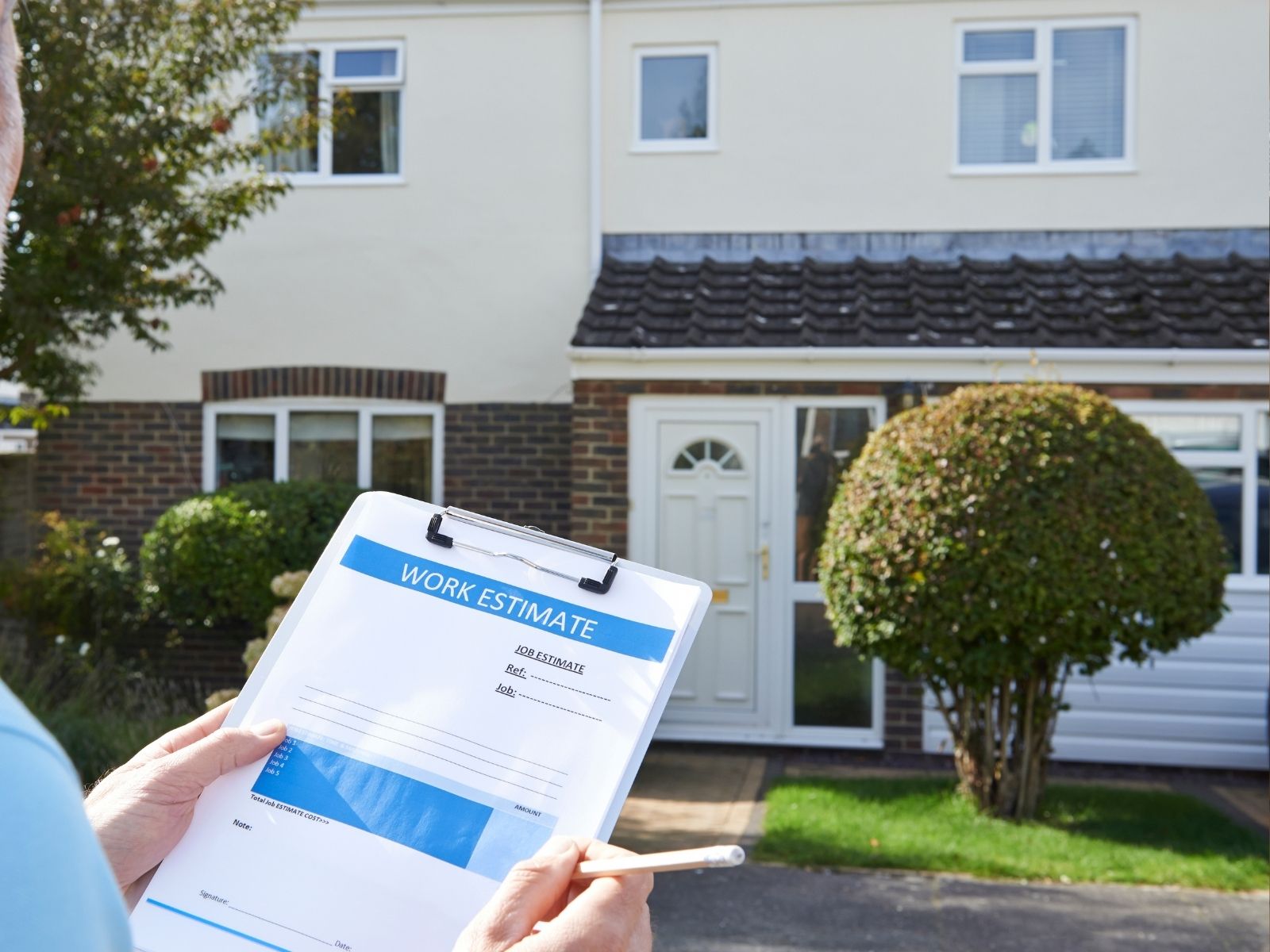 Man inspecting home exterior with clipboard – gutter system assessment and repair planning.